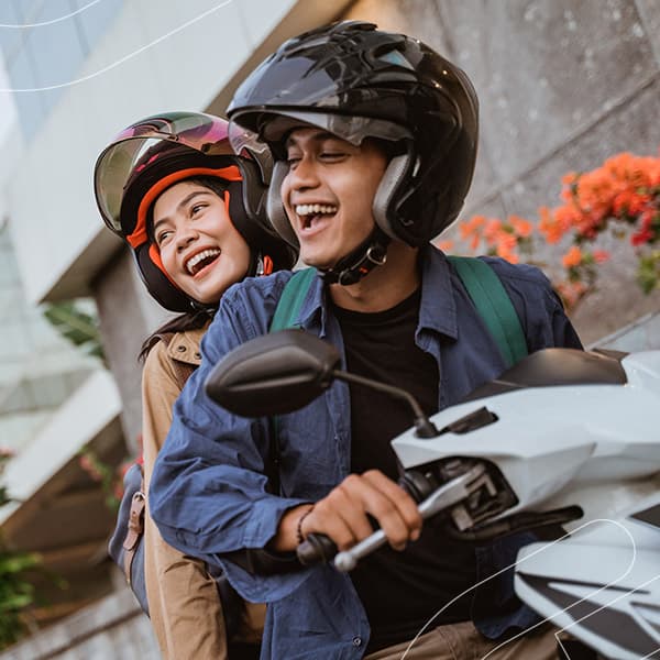 Casal em cima de uma moto, sorrindo.